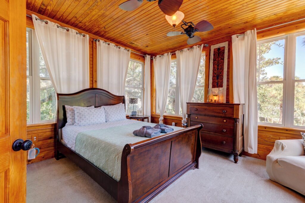 Guest room with a sleigh bed and ceiling fan at Beachside Boutique Inn