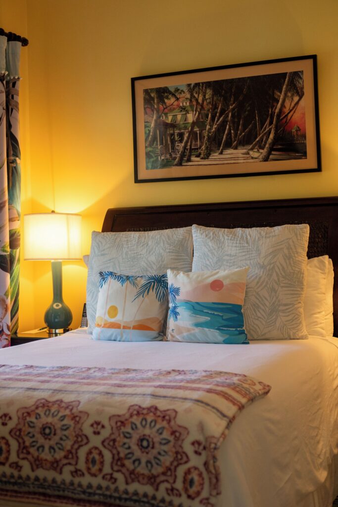 Guest room with ocean-themed pillows at Water’s Edge Inn